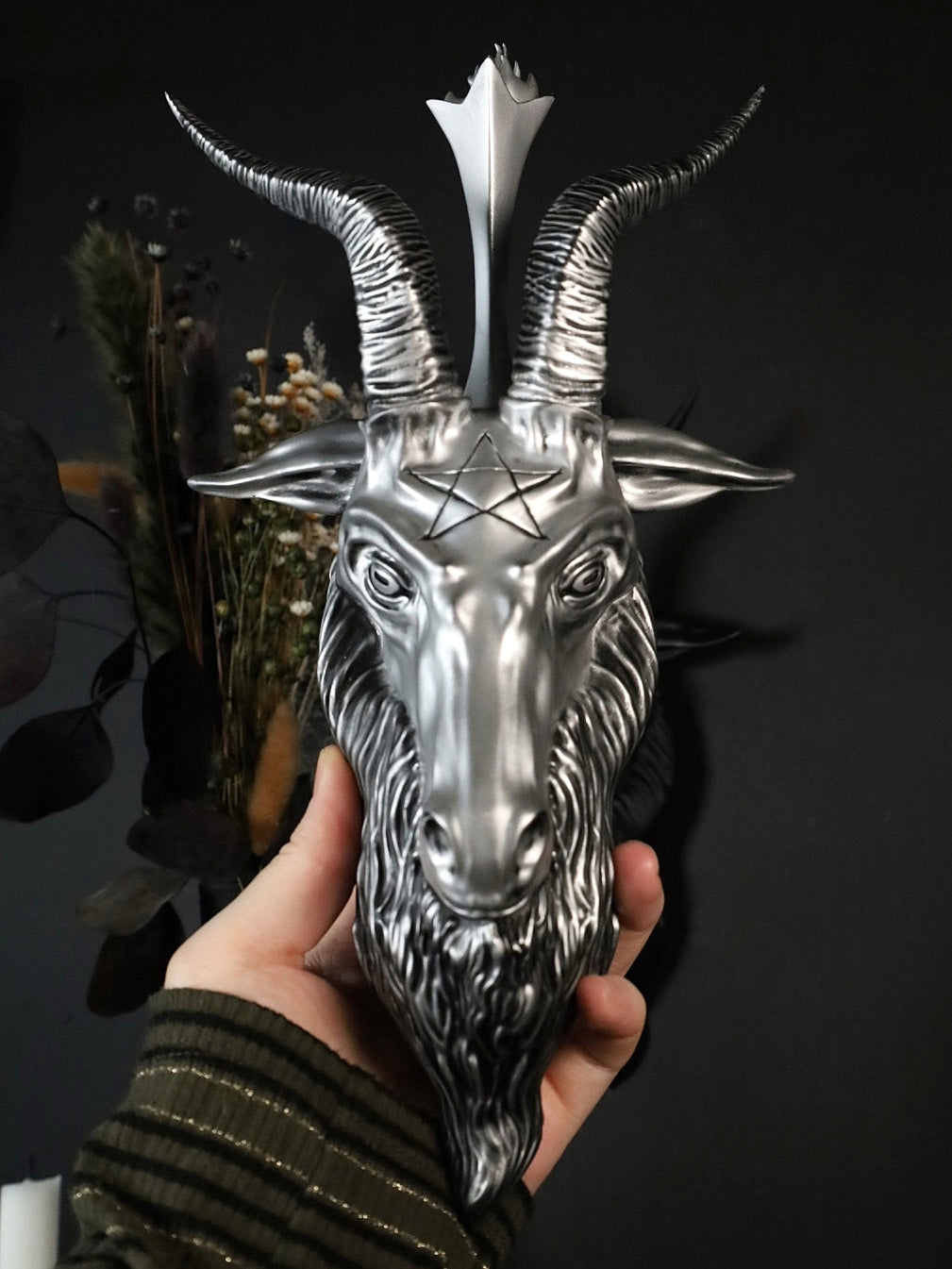 Baphomet goat head sculpture with a pentagram on a dark background
