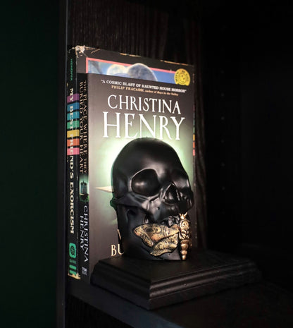 A death moth skull bookend in black and gold.