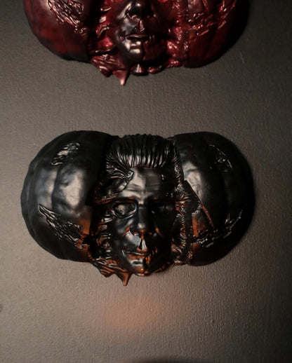 Hand holding a Halloween pumpkin with a Michael Myers face mask inside against a dark background