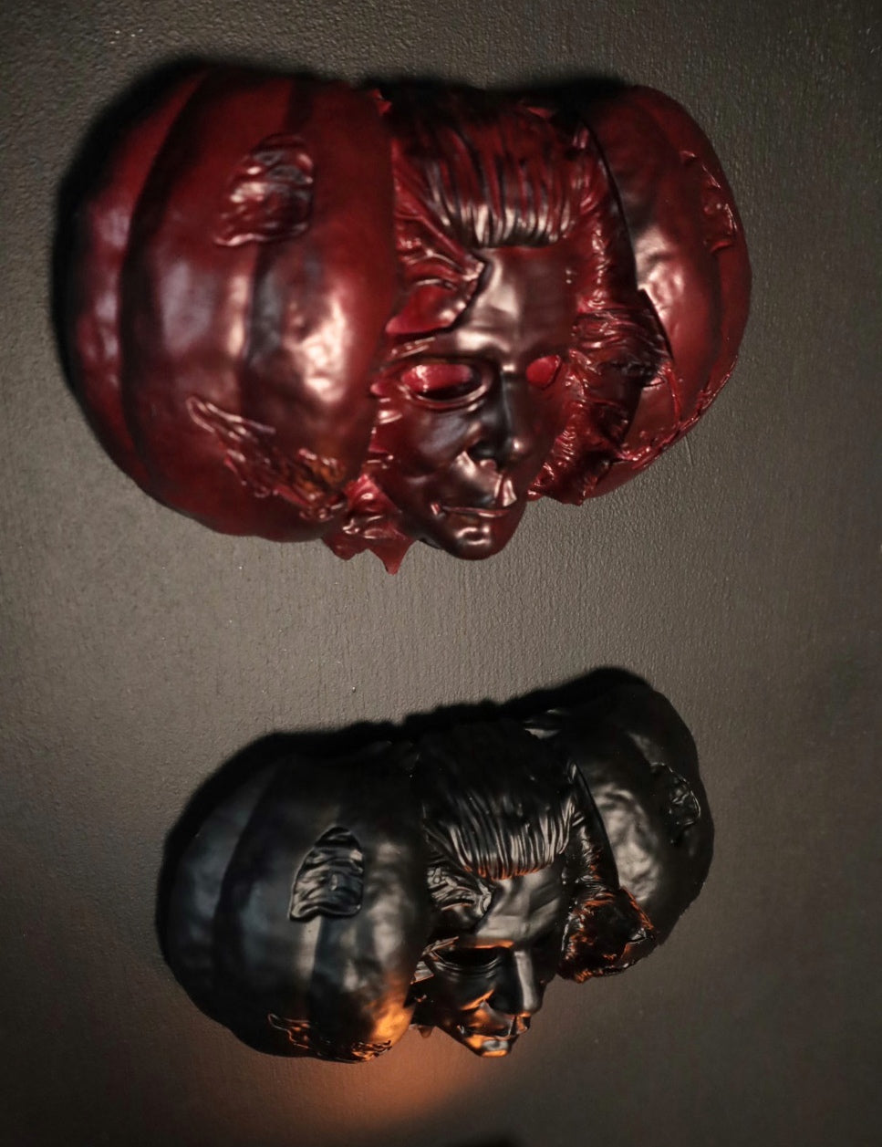 Hand holding a Halloween pumpkin with a Michael Myers face mask inside against a dark background