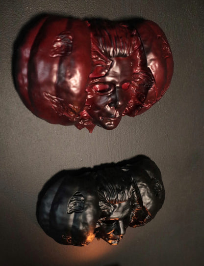 Hand holding a Halloween pumpkin with a Michael Myers face mask inside against a dark background