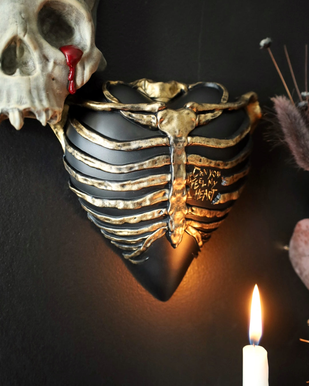 A gothic style wall sconce for your gothic gallery wall shaped like a ribcage over a heart, featuring a black and gold metallic finish.