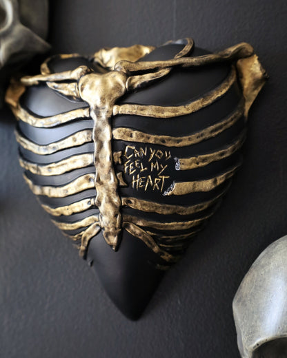 A gothic style wall sconce for your gothic gallery wall shaped like a ribcage over a heart, featuring a black and gold metallic finish.