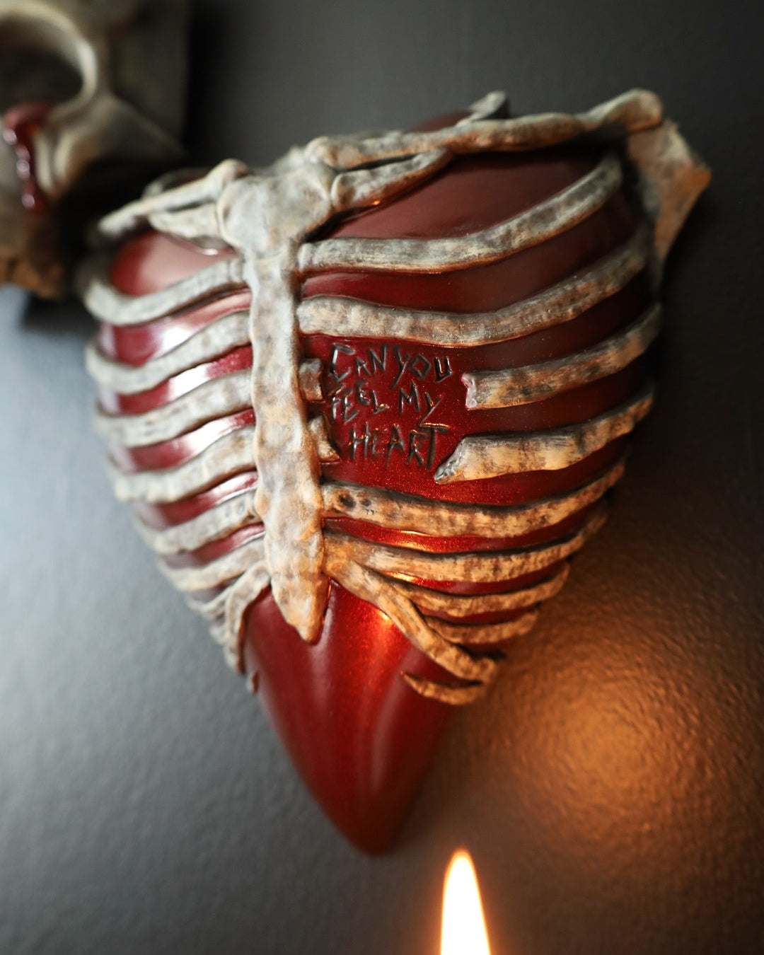 A gothic style wall sconce for your gothic gallery wall shaped like a ribcage over a heart, featuring a red and bone painted finish.