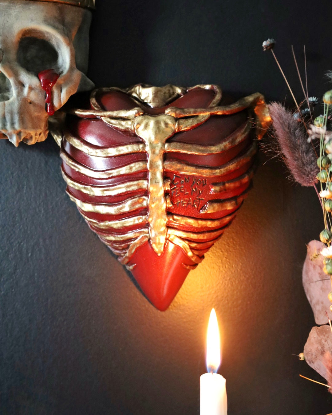 A gothic style wall sconce for your gothic gallery wall shaped like a ribcage over a heart, featuring a red and gold metallic finish.