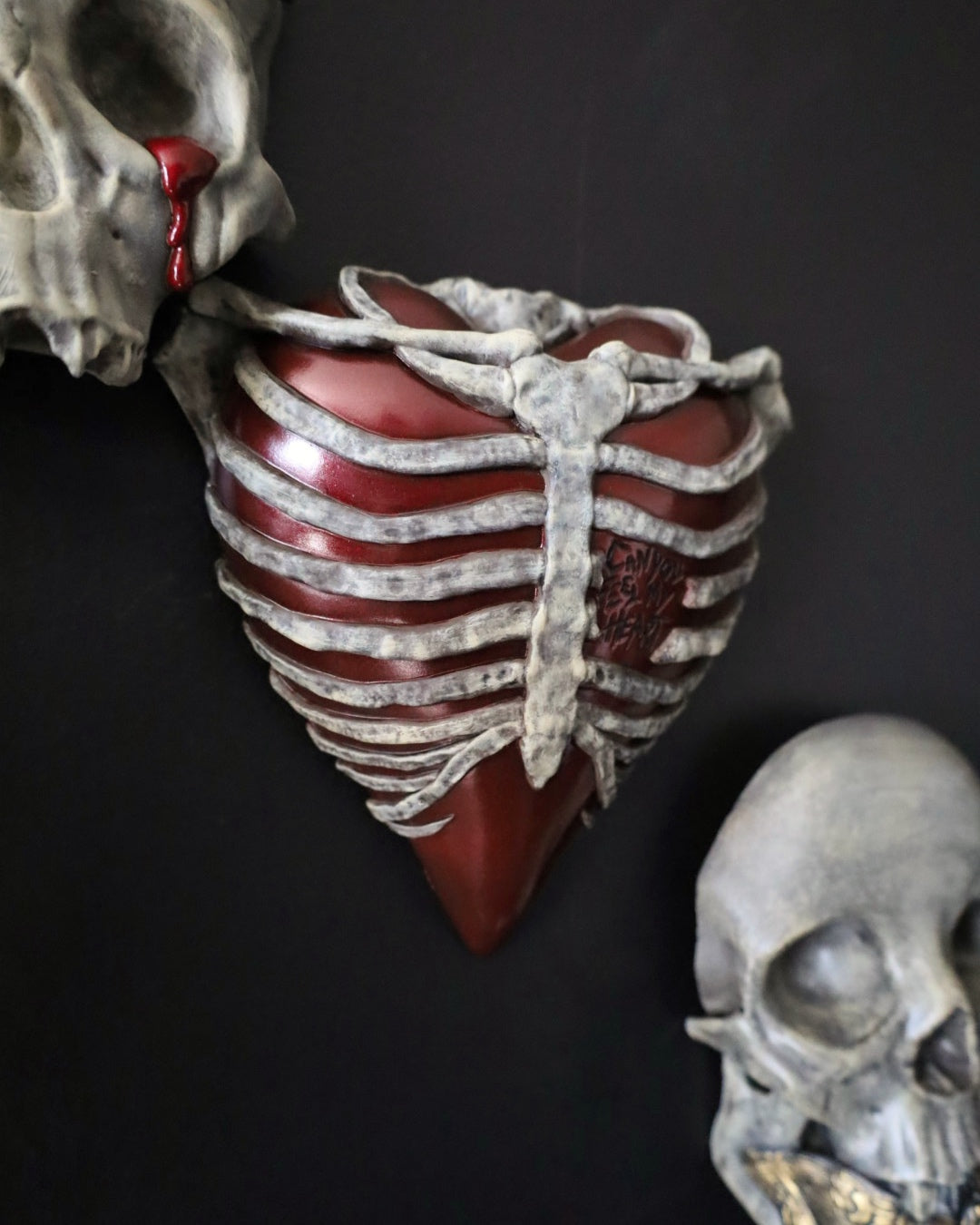 A gothic style wall sconce for your gothic gallery wall shaped like a ribcage over a heart, featuring a red and bone painted finish.