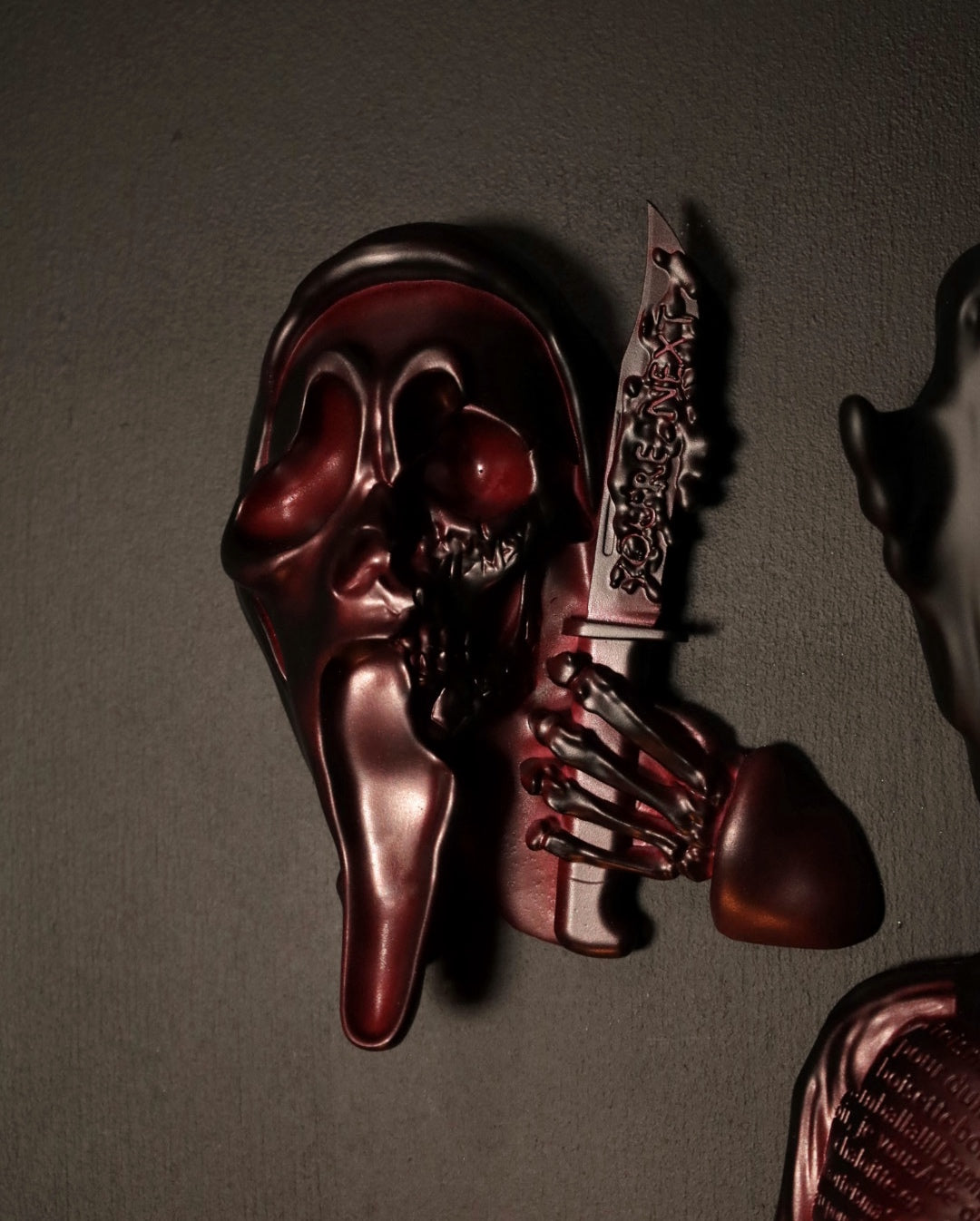 Scream Ghostface mask with a knife and hand holding it against a dark background