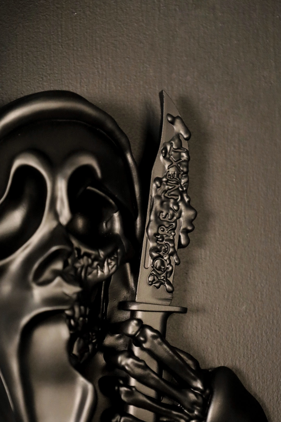 Scream Ghostface mask with a knife and hand holding it against a dark background