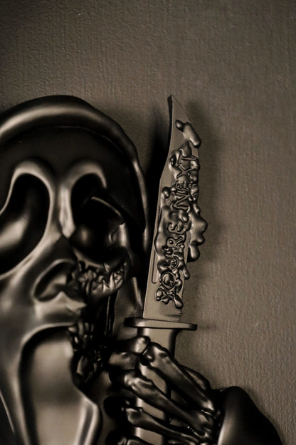 Scream Ghostface mask with a knife and hand holding it against a dark background