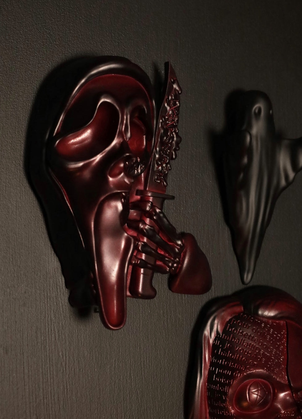 Scream Ghostface mask with a knife and hand holding it against a dark background