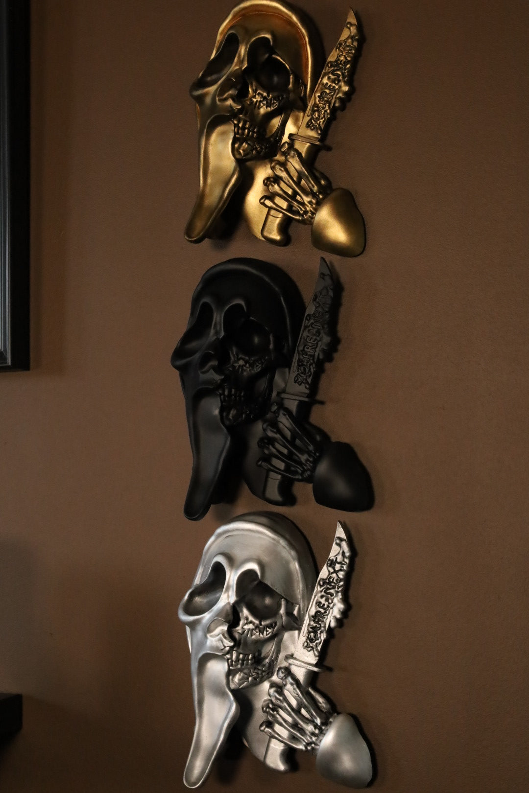 Scream Ghostface mask with a knife and hand holding it against a dark background