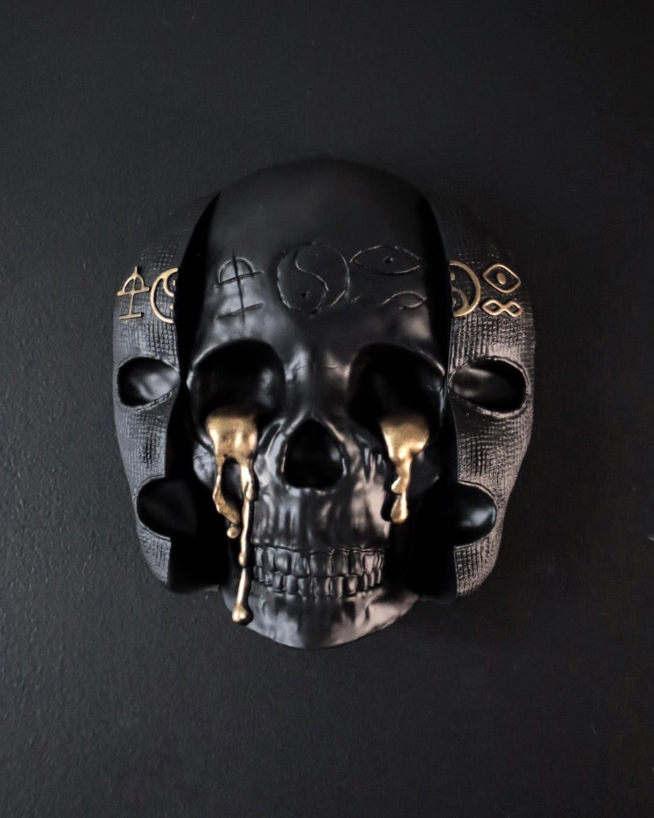 Black skull wall decoration with gold accents on a dark background inspired by Bad Omens 