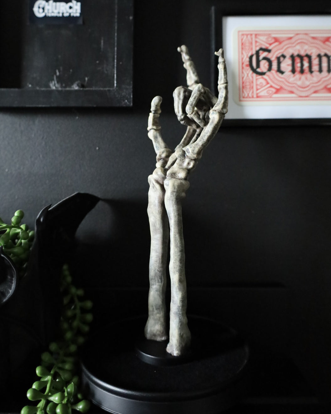 A skeleton hand jewellery stand or ornament holding silver chains and rings, set on a black round base.