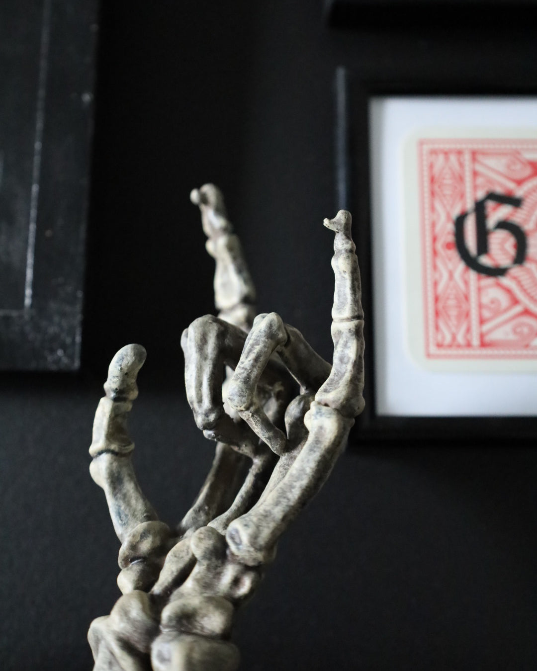 A skeleton hand jewellery stand or ornament holding silver chains and rings, set on a black round base.