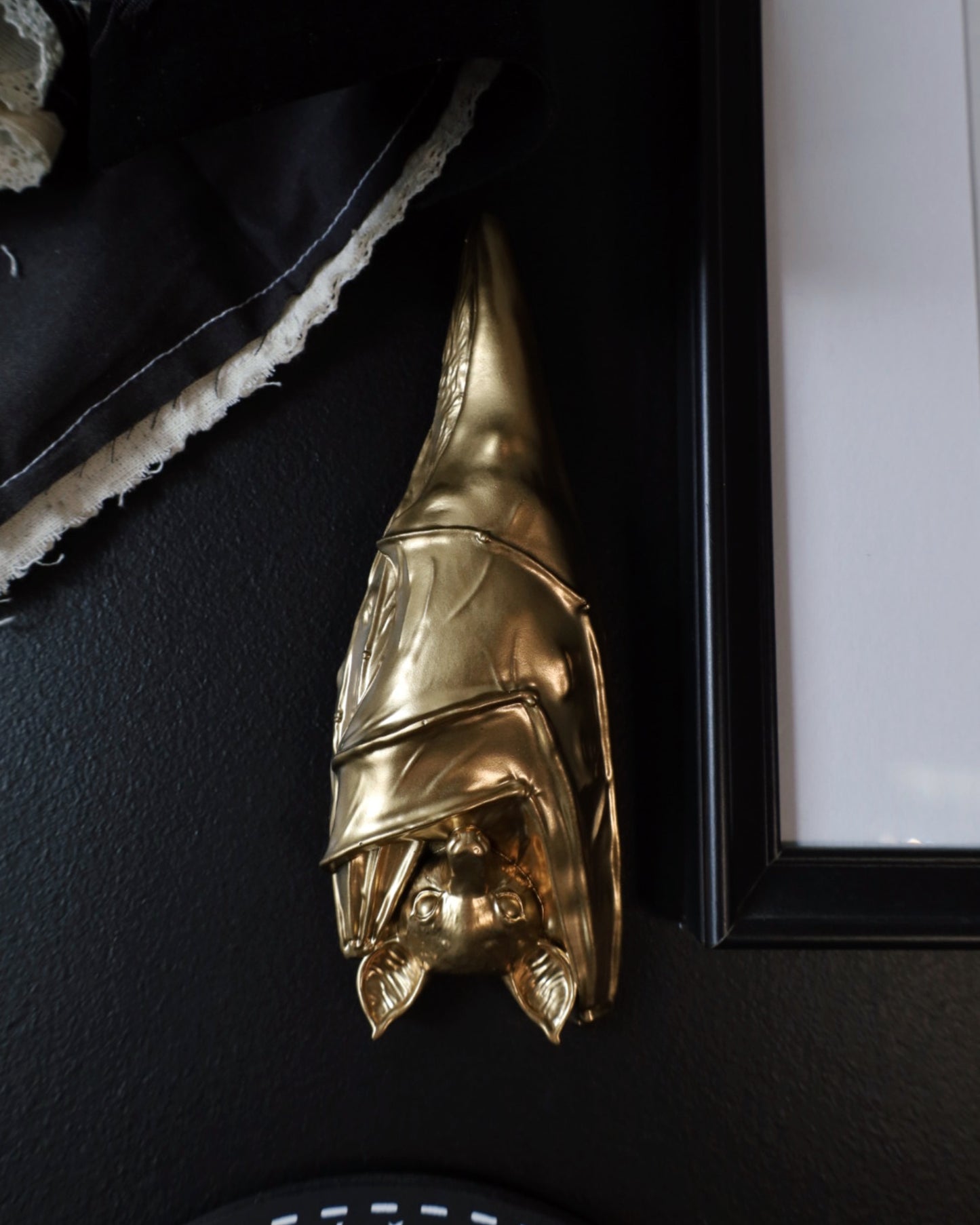 Gold sleeping hanging bat decorative wall hanging on a black surface