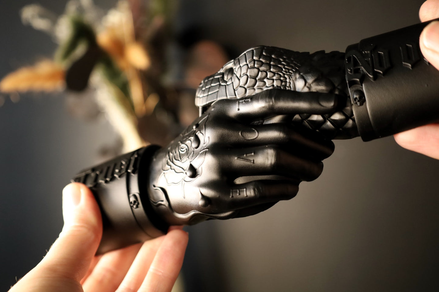 A tattooed hand wall hanging with a snake biting and the text trust no one. 
