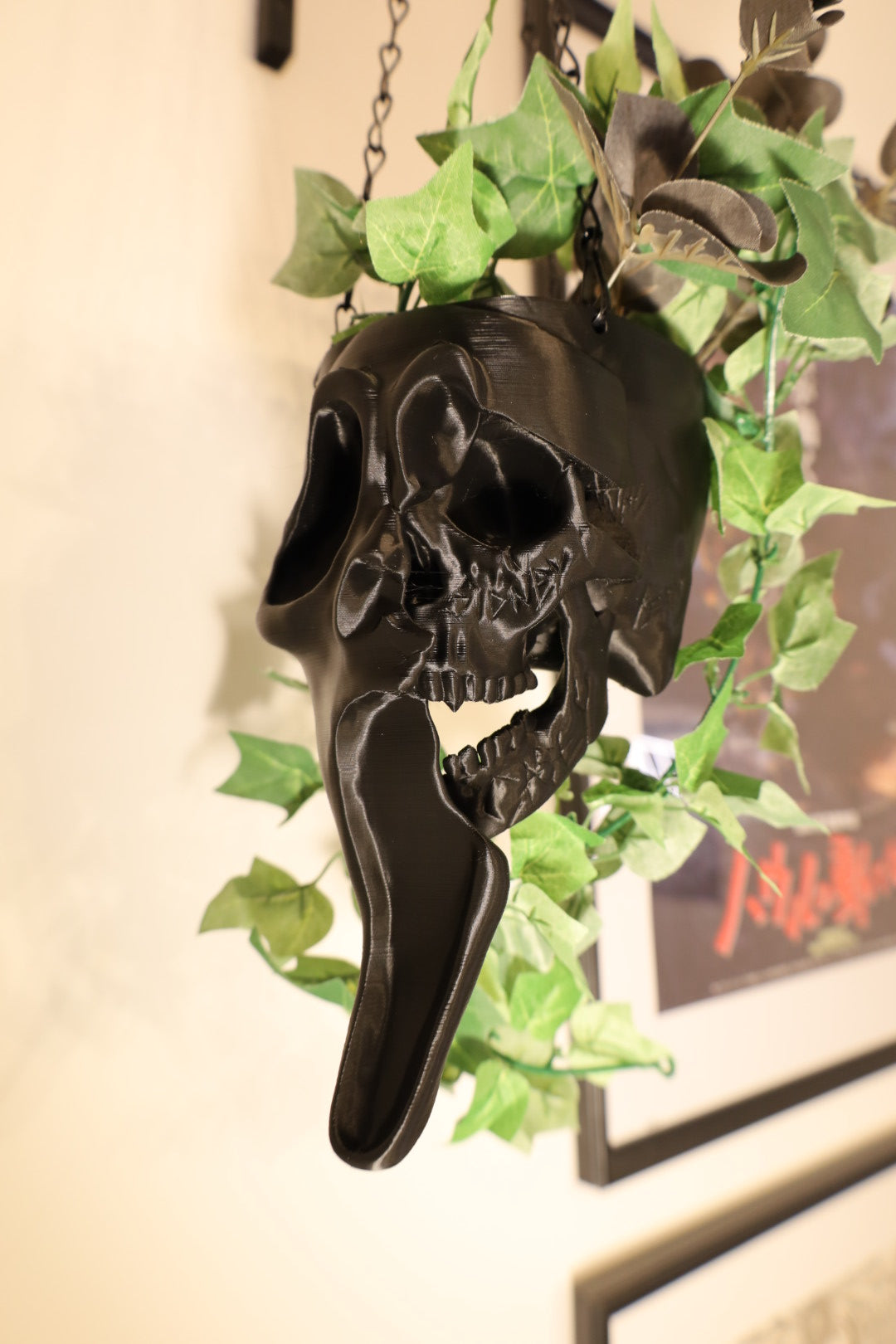 Black ghostface hanging planter with green plants coming out of it 