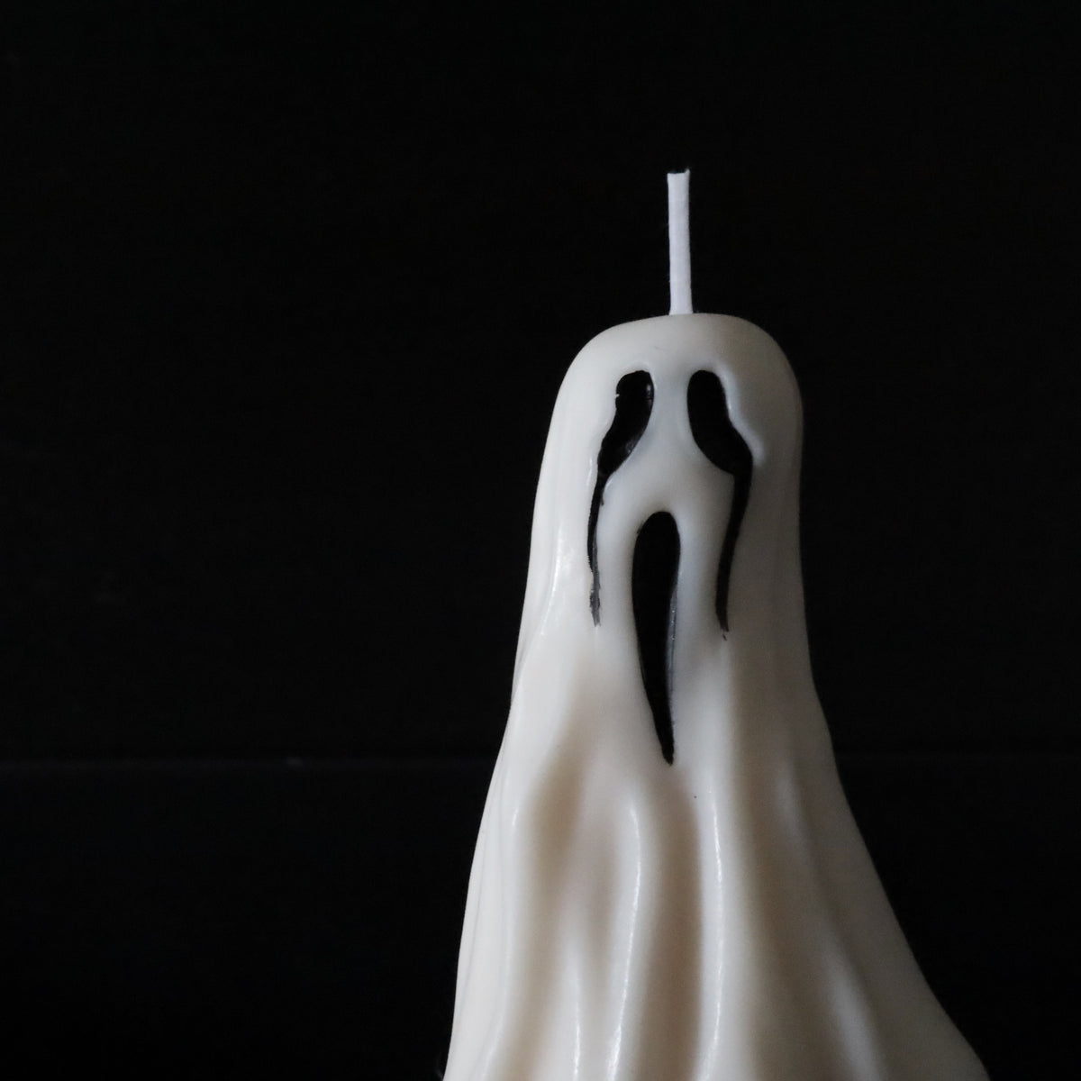 A white ghost pillar candle with pumpkin spice