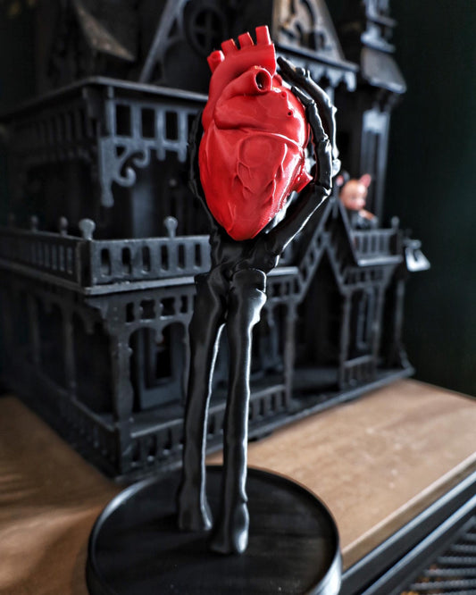 A skeleton hand jewellery stand/ornament holding an anatomical heart, gothic home decor
